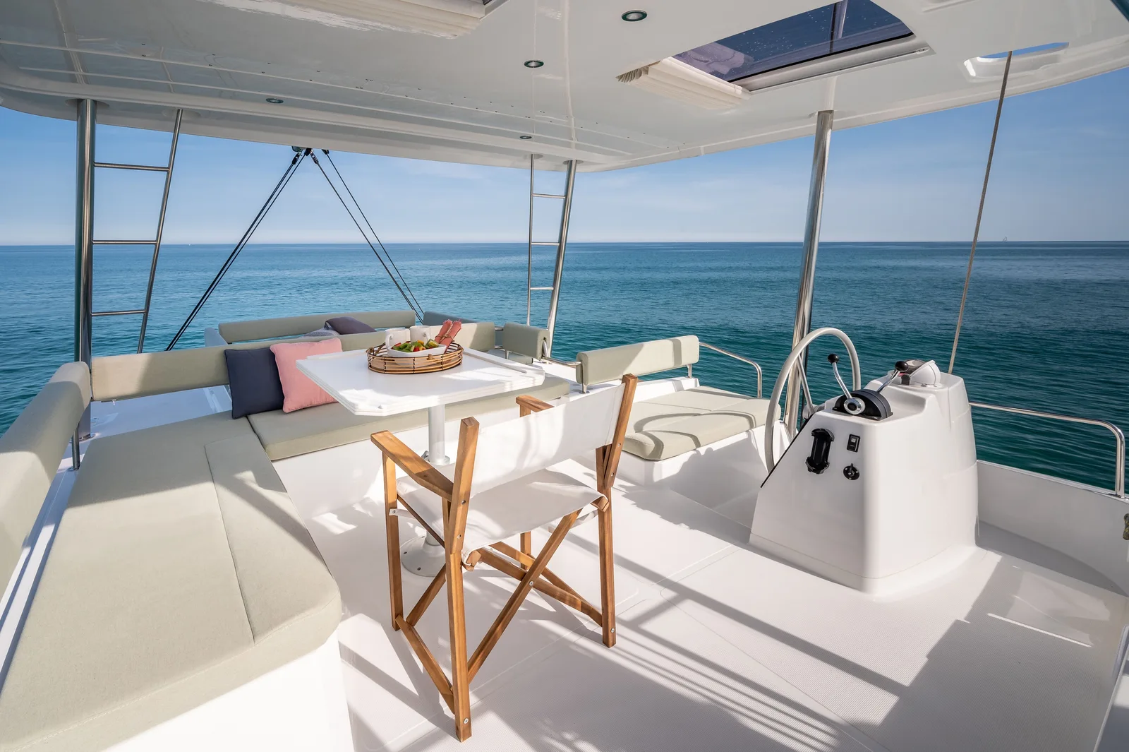 Bali 4.6 flybridge with a large cushioned bench, table and seating beside the helm